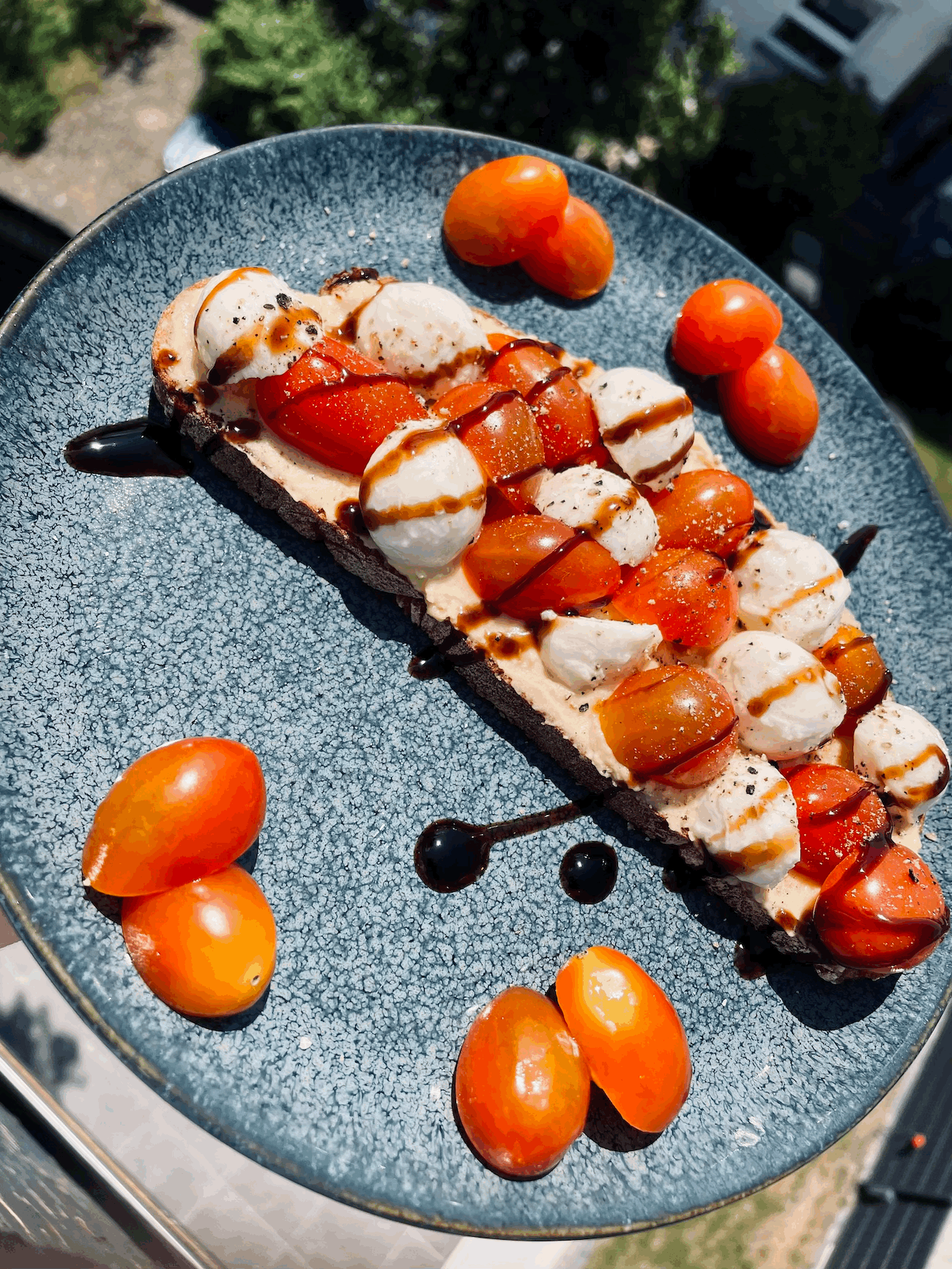 Brot mit Hummus, Cherrytomaten und Mozzarellaballs belegt. Gesalzen und Gepfeffert.