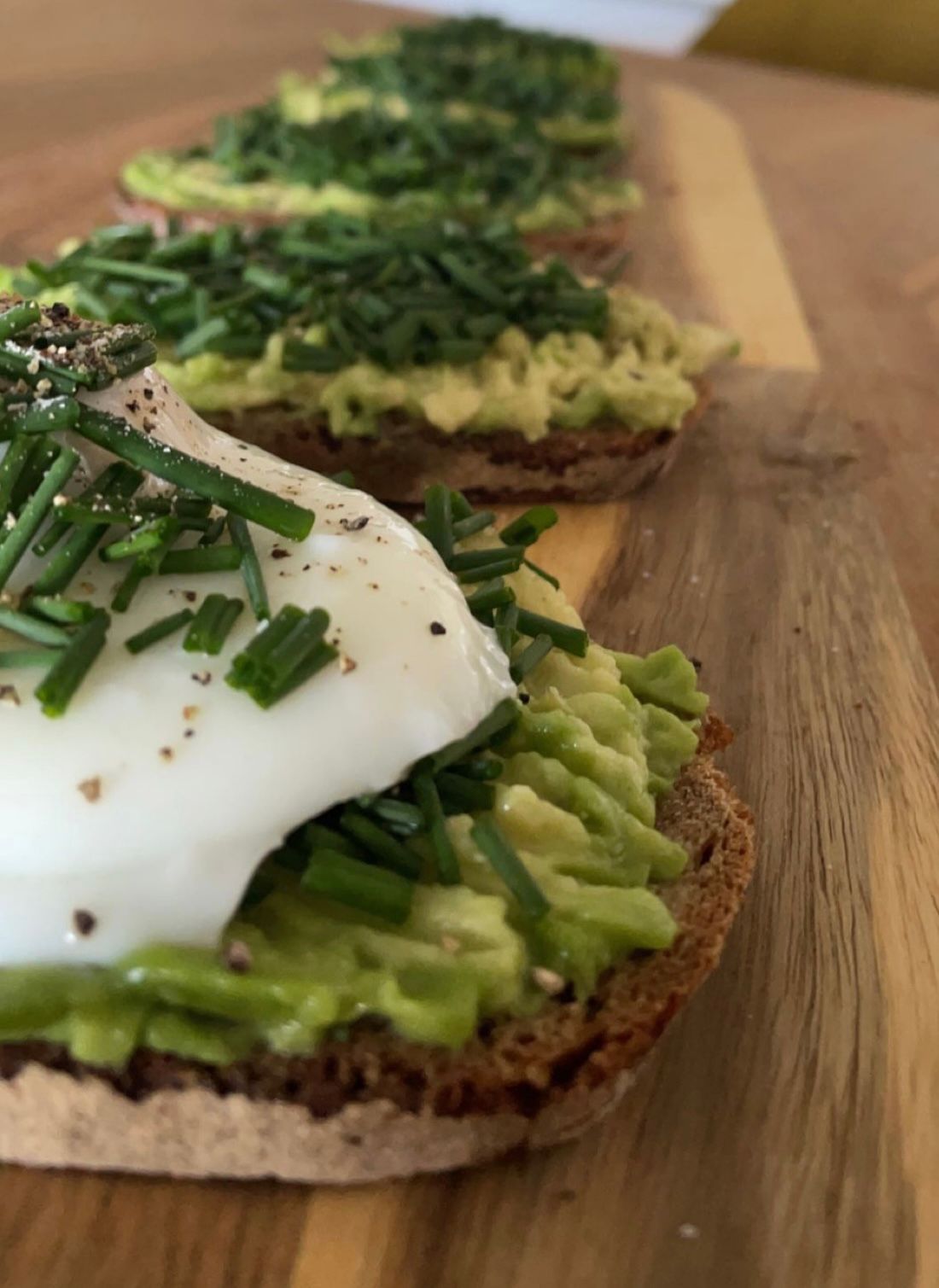 Es sind 5 Brote mit Guacamole beschmiert zu sehen, das Erste in der Reihe hat noch ein pochiertes Ei oben drauf.