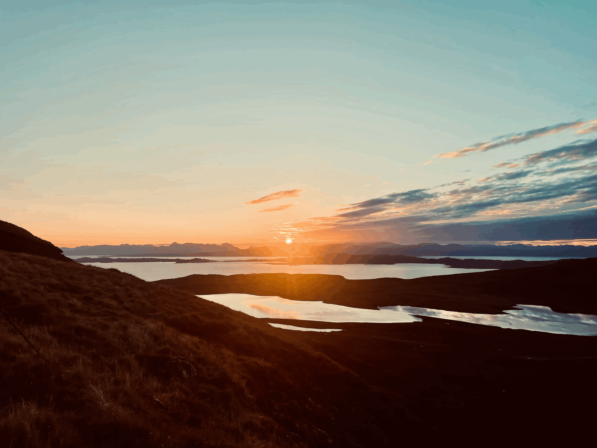 Die Aussicht von einem Hügel. Die Sonne geht gerade auf und spiegelt sich orange im den drei Wasserbecken.