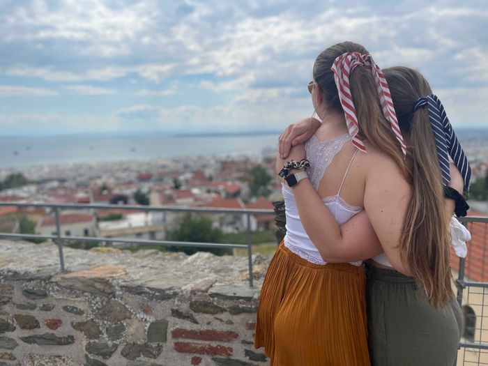 Zwei junge Frauen stehen mit dem Rücken zum Betrachter. Ihr Blick ist auf die Stadt Thessaloniki und das Meer gerichtet.