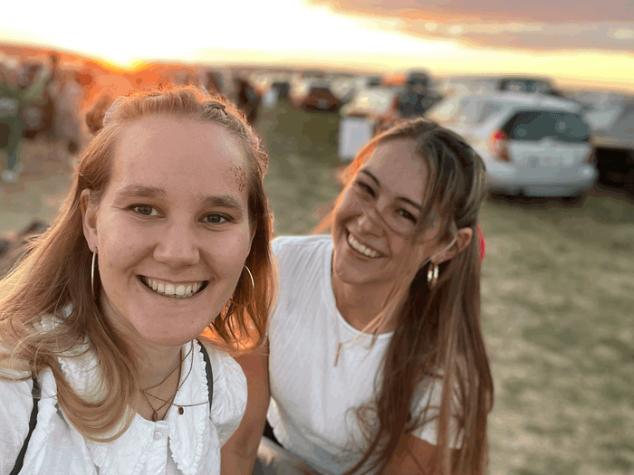 Ein Selfie zeigt zwei lächelnde Frauen auf einem Campingplatz.