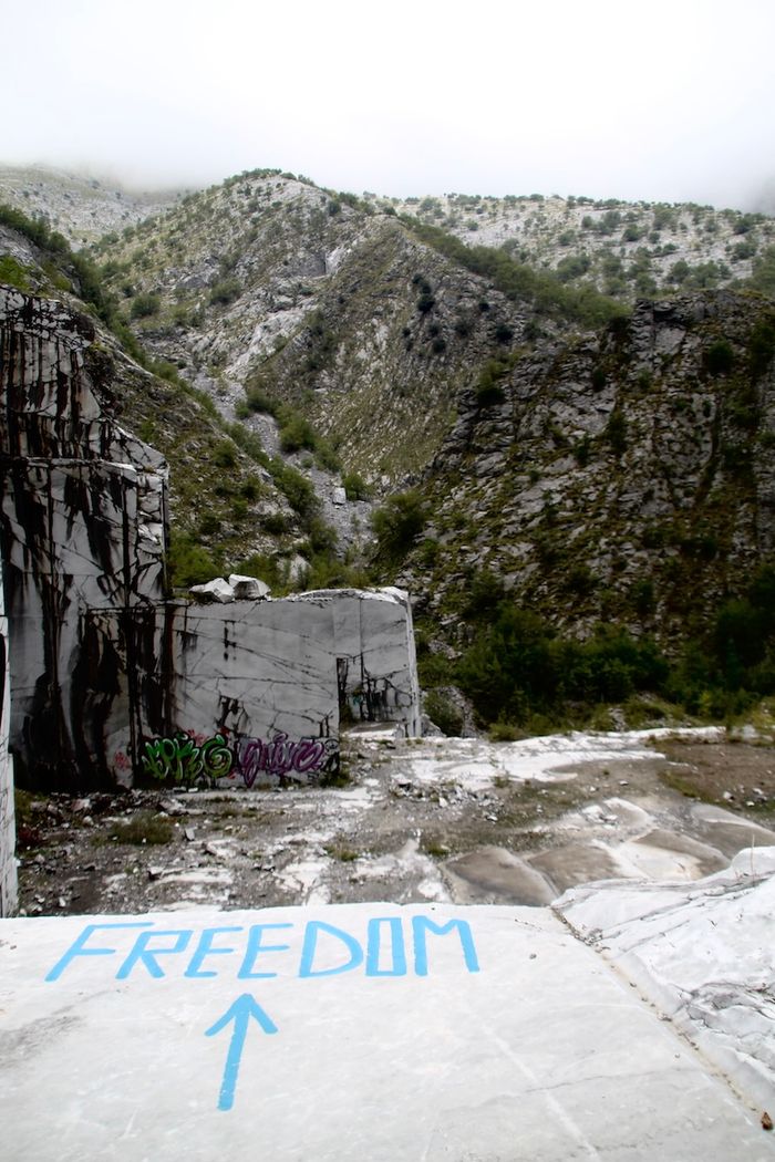 Bild aufgenommen im Steinbruch Henraux: Auuf weißen Carrara-Marmor sind ein Pfeil und das Wort "Freedom" gesprayt