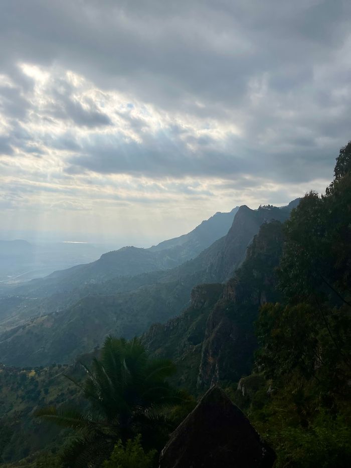 Aussicht vom Usambara-Gebirge auf das Tal. Die Sonne bricht durch die Wolken.